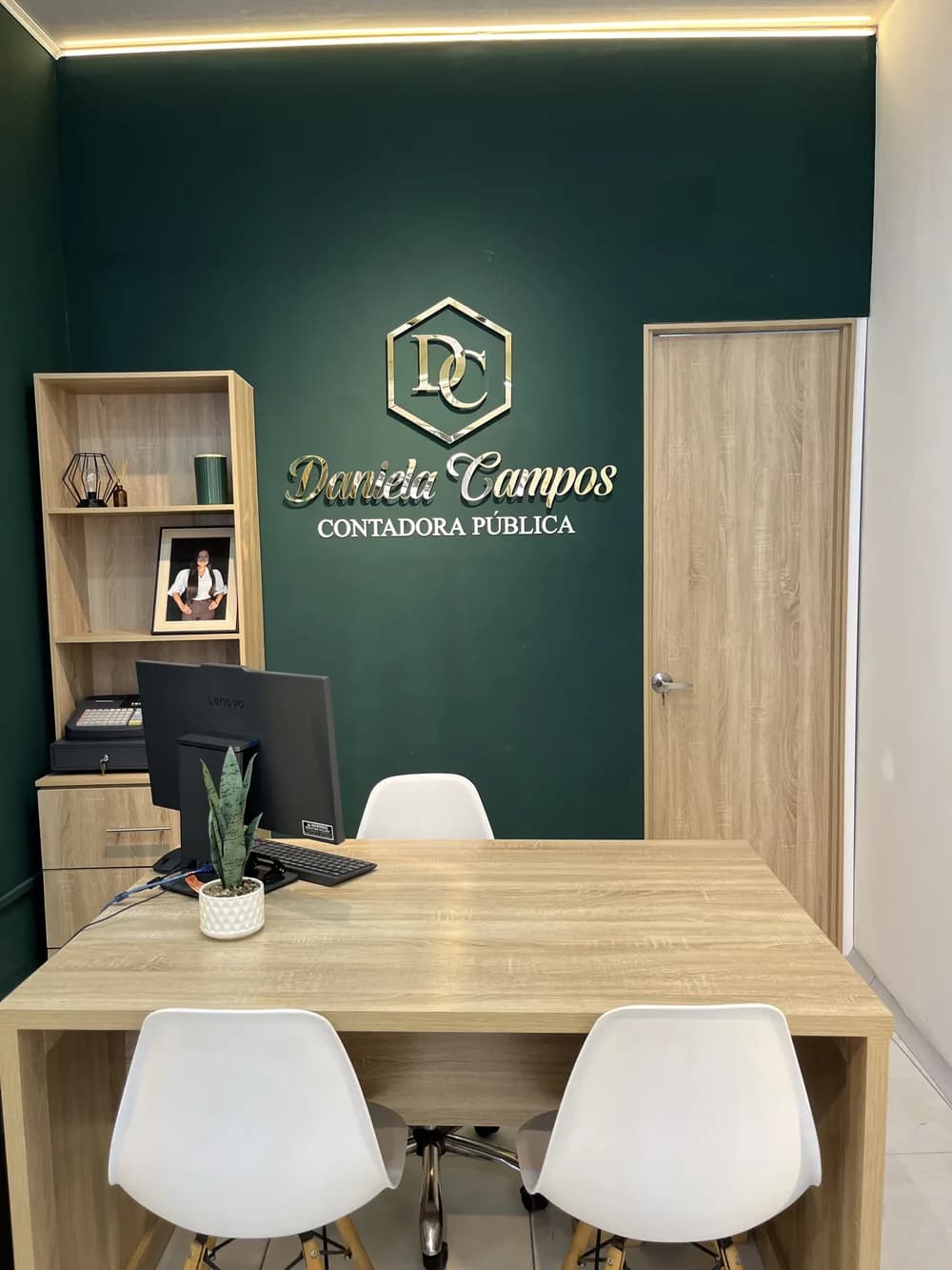 Área de atención con el logo de Daniela Campos en la pared de la oficina